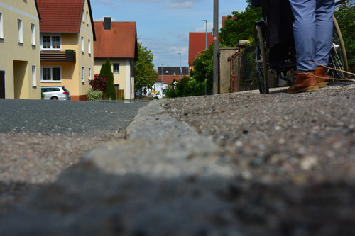 Rolli auf abschüssigem, baufälligem Gehweg -  selbst für Fußgänger:innen gefährlich 