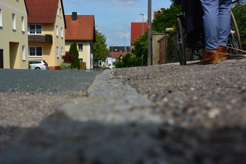 Rolli auf abschüssigem, baufälligem Gehweg -  selbst für Fußgänger:innen gefährlich