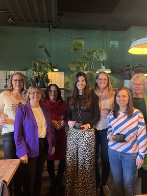 Gruppenfoto mit sechs Frauen beim politischen Treffen unter dem Motto Politics und Pancakes. Die Frauen halten Getränke in der Hand und lächeln.