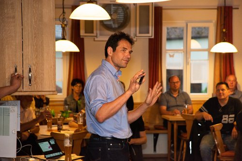 Martin Stümpfig referiert, mit einigen der knapp 40 interessierten Zuhörer:innen im HIntergrund  &nbsp;© Raphael Rother