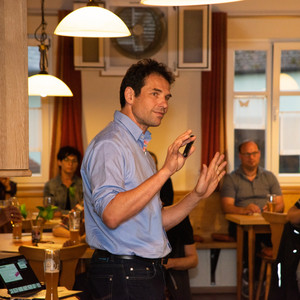 Martin Stümpfig referiert, mit einigen der knapp 40 interessierten Zuhörer:innen im HIntergrund  &nbsp;© Raphael Rother